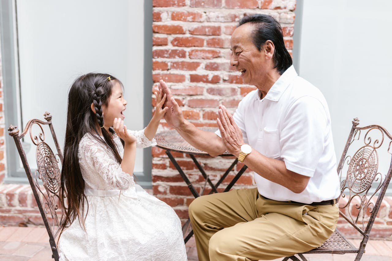 Grandfather and granddaughter share a happy moment playing together outdoors.